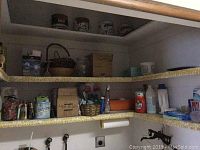 Photo showing multiple shelves filled with various cleaning and household products including labeled boxes and liquids.