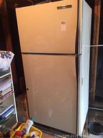 Front view of the refrigerator freezer in cream/off-white color with top freezer compartment.