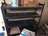 Black metal shelving unit shown with three shelves and empty storage space