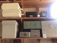 Ten metal and plastic storage containers of various sizes and colors arranged on wooden shelves.