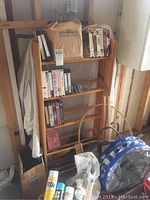 Wide view of all items stacked on wooden shelf and floor, showing baskets, VHS tapes, cleaning supplies