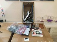 Overview of lot items including zip lock bag with phone cases, boxed software, and other small items on table.