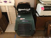 Green Petmate Pet Porter dog kennel with metal front door side view, black pet carrier bag on top