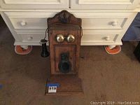 Front view of the vintage wooden wall phone with two brass bells and mouthpiece.