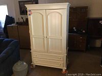 Front angle view of white media cabinet showing double doors, two drawers, and round feet.