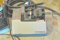 Ingersoll Rand air compressor unit with visible fan vents and handle, placed on floor with cables