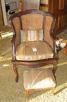 Wicker arm chair with carved wooden frame and cushion with matching pillow. Chair has woven wicker back and sides.