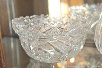 Close-up of a clear crystal cut glass bowl with star and fan cut patterns and scalloped edges.
