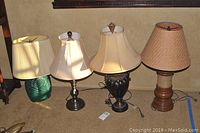 Four assorted lamps on floor showing varying bases and lampshades