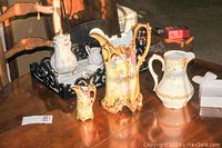 Photo showing hand painted Laffon pitcher, creamer, a white floral creamer or teapot, and Nippon chocolate pot on wooden tray on a table with napkin holder.