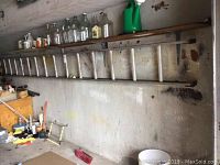 Side view of long aluminum ladder on wall showing wear marks and rubber end caps