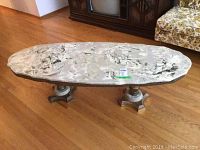 Side angle view of the marble coffee table showing the top and one pedestal base