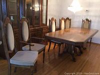 Six oak dining chairs around a dining table in a room with hardwood floor and chandelier, showcasing style and condition