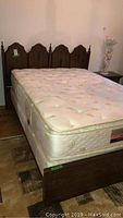 Wooden double bed set with headboard, footboard, rails, and mattress in place shown from a side angle.