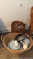 Wicker basket filled with Royal Doulton Simply Platinum cups, saucers, plates, assorted dishes, frying pan, wok, and cooking pot. Brown bag behind the basket contains glass stemware.