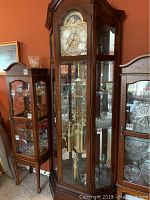 Full view of clock and display case showing wood finish and glass panels