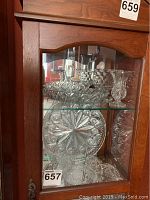 Full view of wooden cabinet with shelves containing various vintage cut glass items including bowls, vases, and platters.