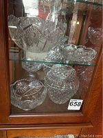 Group shot of all vintage cut glass items on a cabinet shelf