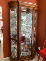 Full front view of china cabinet showing curved glass front, wood veneer frame and interior shelving