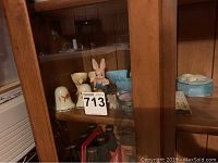 Photo of wooden display cabinet shelf with various collectible figurines and small decorative items including a bunny figurine, elephant figurines, and a white ceramic shaker.