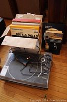 Photo showing the JVC JL A20 turntable with several vinyl record albums behind it and two books standing upright to the side.