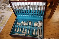Open wooden canteen box displaying upper and lower trays of flatware