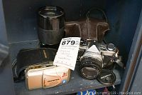 Two film cameras, telephoto lens, cases, lens cap on shelf