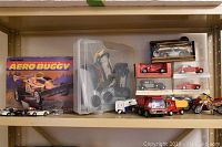 Wide shelf view showing boxed Radio Shack Aero Buggy and several toy trucks, motorcycles, and small vehicles.