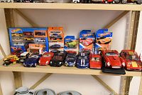 Shelf display with multiple die cast model cars and boxed car sets including Hot Wheels and Matchbox brands.