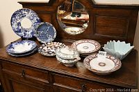 Full display of china set on wooden dresser including plates, tureen, and bowl.