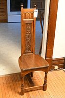 View of wood chair showing carved back panel, turned legs, and seat shape.