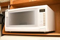 Front view of Panasonic white microwave showing door with mesh screen and overall condition.