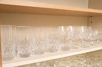 Top shelf displaying tall crystal tumblers with diamond cut patterns in a row.