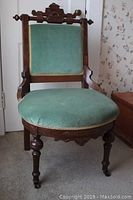 Frontal view of the East Lake chair showing green velvet upholstery and carved wooden frame.