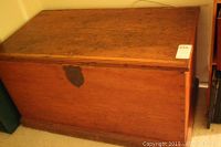 Front view of the antique wooden chest showing hinged top, metal keyhole plate, and wood grain