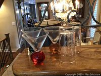 Three martini glasses on wooden surface; two with red spherical bases, one amber base