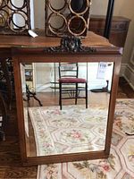Front view of rectangular beveled mirror with carved wood frame and crest, shows wear consistent with age