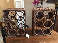 Two Pottery Barn wicker wine racks, rectangular with circular bottle holders, shown side by side on wood surface.