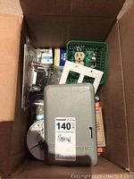 Cardboard box containing electrical components including timer, outlet, faceplate, bulbs, and socket