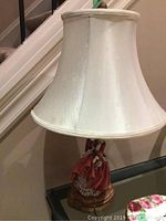 Full view of lamp with cream bell shade and figurine base