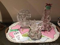 Three clear glass perfume bottles arranged on a decorative tray with measured notes, showing the variety of shapes and sizes of the items.