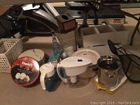 Various kitchen items including Dansk baking dish, enamel pots, Braun blender, salad spinner, soap dispenser and waste basket in indoor room setting