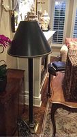 Full view of the floor lamp showing black conical shade and black cylindrical stand in living room setting