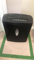 Photo of full paper shredder from front, showing black body with window to view contents