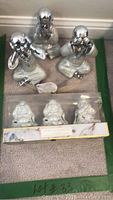Photo showing three loose silver-tone ceramic figurines representing 'Hear No Evil, See No Evil, Speak No Evil' monkeys and a box of three packaged white ceramic scented figurines.