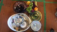Photo showing assorted large platters, tiered serving tray, ice cream bowls, and plastic fruit in glass bowl