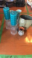 Front view of lot showing two teal candles in ribbed glass holders and 3 ceramic vases plus small pitcher.