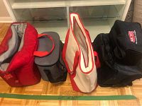 Photo showing five assorted soft cooler bags of various sizes and colors, placed side by side on a wooden floor.