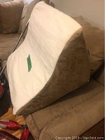 Side view of the foam wedge pillow showing the beige top and brown fabric sides, triangular shape designed to elevate upper body.