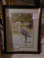 Framed lithographic print of a blue heron standing in water.